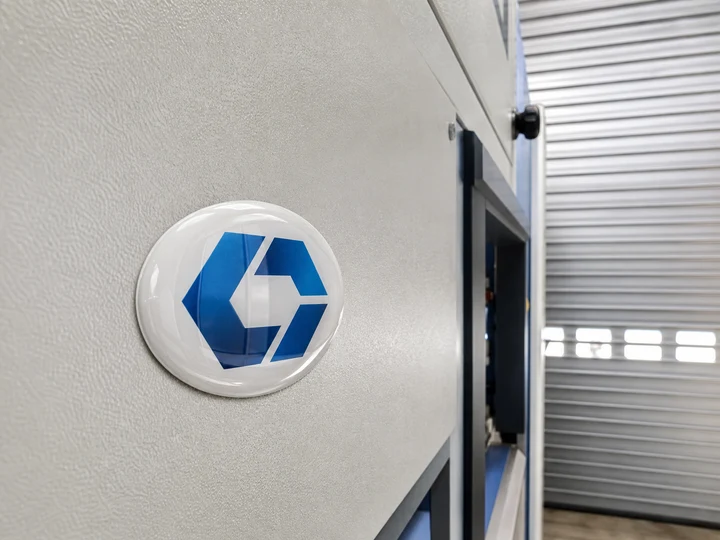 Gewölbter Gelaufkleber als Markenemblem auf einer Maschine neben einem Rollladen