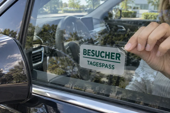 Von innen abnehmbare transparente Adhäsionsfolie mit Besucherhinweis hinter einer Autoscheibe