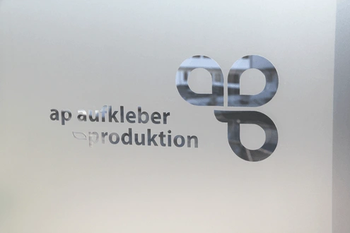 Milchglasfolie mit ausgeschnittenem Logo auf einer Glasscheibe